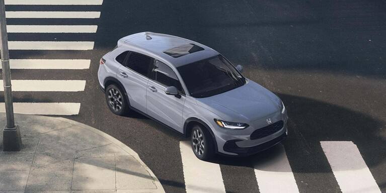 2027 Honda HR-V EX-L in Urban Gray Pearl high-angle view driving through a city intersection (Subcompact Crossover SUV).