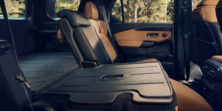 2027 Honda Passport TrailSport Elite folded rear seats showing flat cargo floor and brown leather accents (Mid-Size SUV).